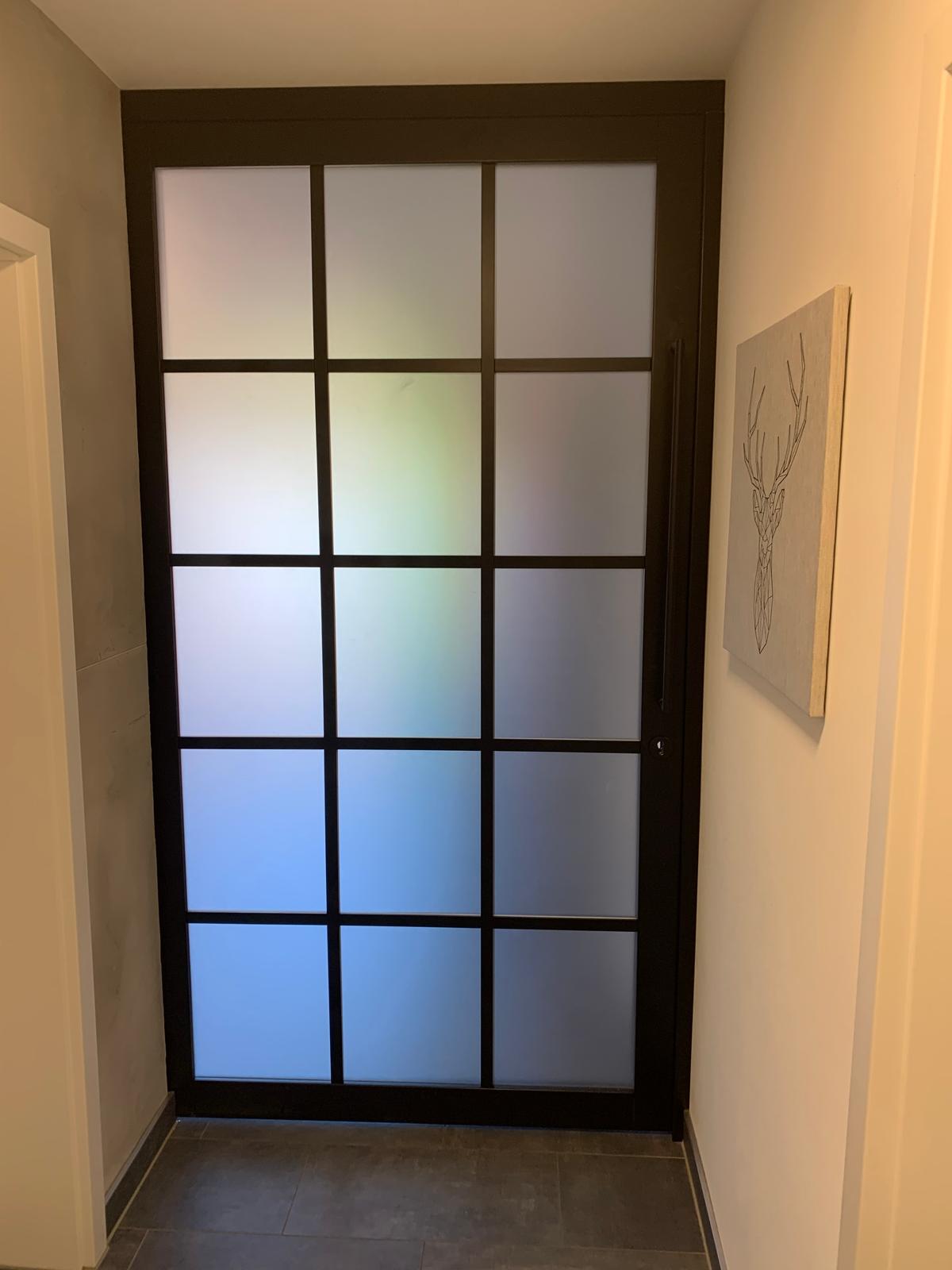 Schwarze Glastür mit mattem Einsatz und Gittern, daneben ein Hirschbild an der Wand