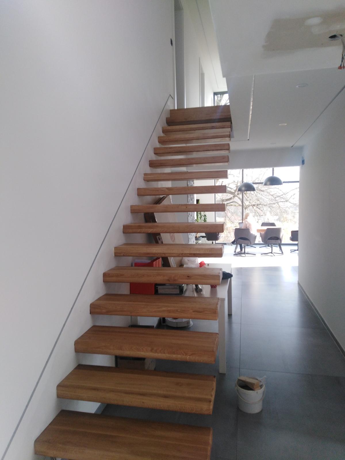 Eine moderne freitragende Holztreppe mit hellen Stufen in einem minimalistisch gestalteten Flur
