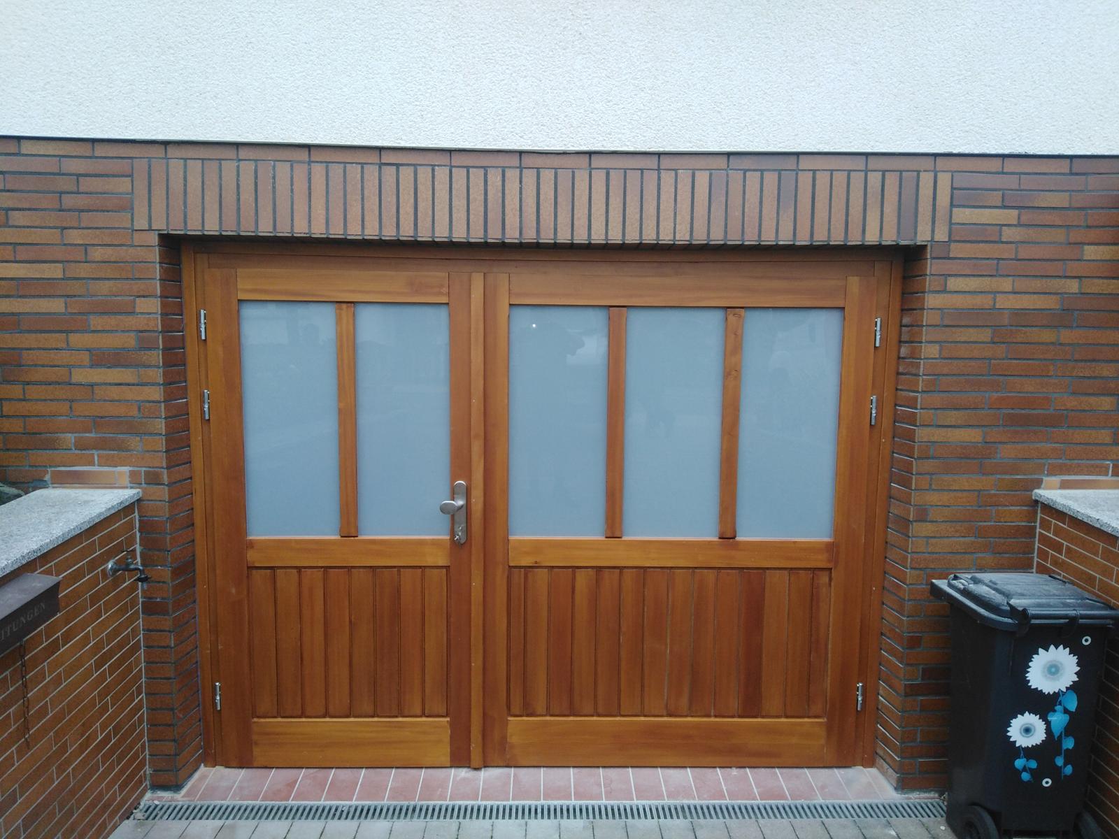 Doppelflügeltor aus Holz mit Milchglasfenstern und braunen Ziegelwänden umliegend