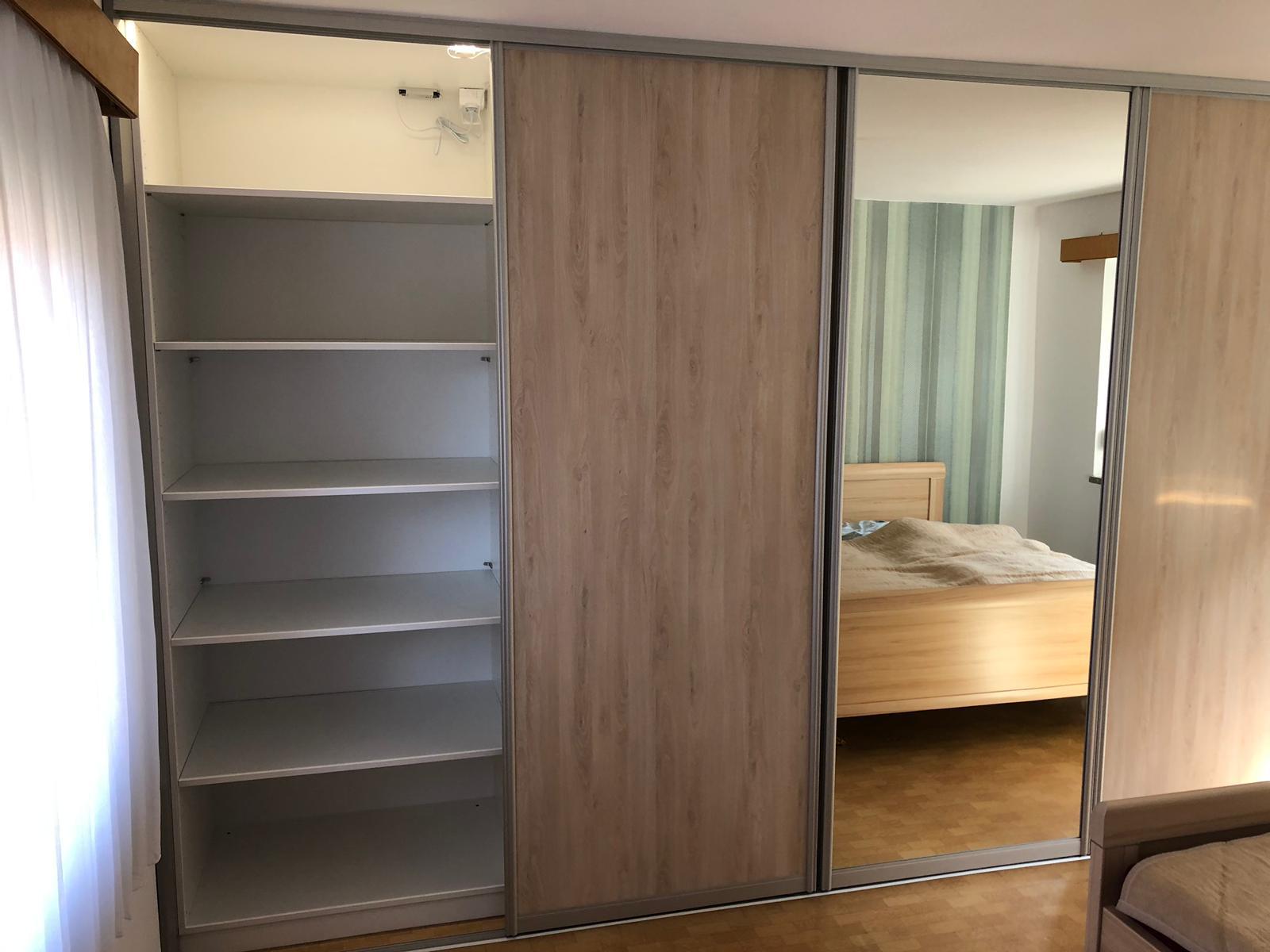 Ein geräumiger Kleiderschrank mit offenen Regalen und einer Spiegeltür im Schlafzimmer